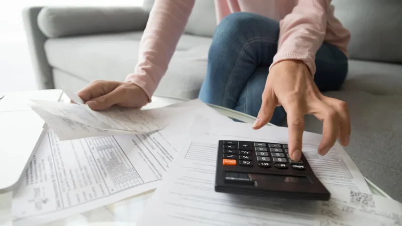 Hands sorting bills and receipts with a calculator